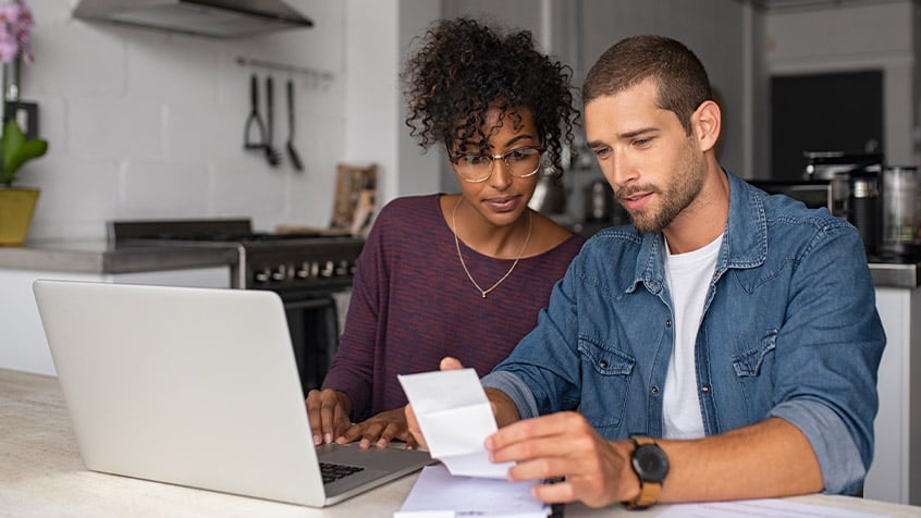 young couple reviewing finances and laptop