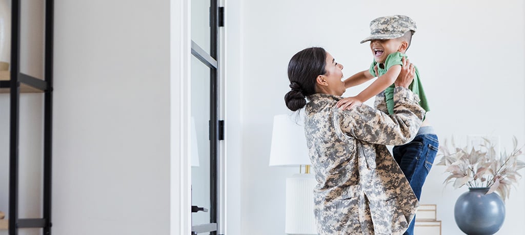 A heartwarming embrace between a mother in uniform and her giggling child, donning a matching cap.