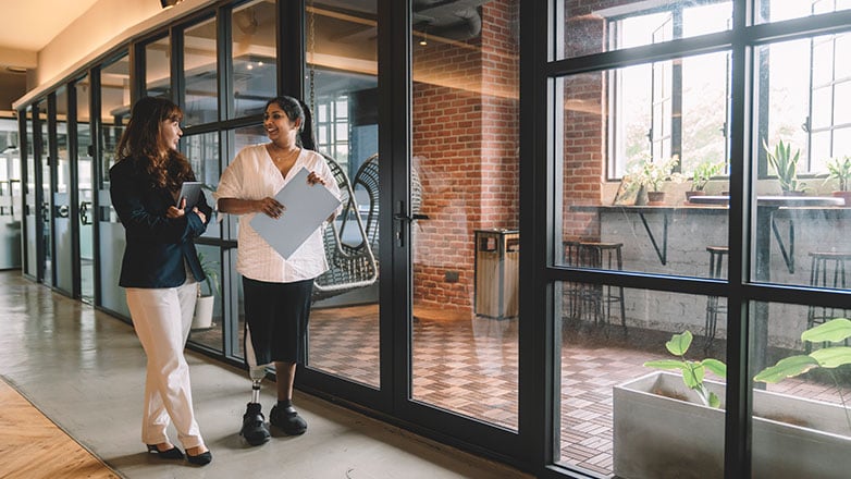 Work colleagues walk down the hallway of their workpace together.