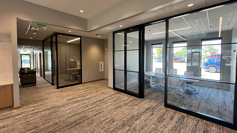 A carpeted hallway with two glass doors leading to offices, one with a view of a parking lot.